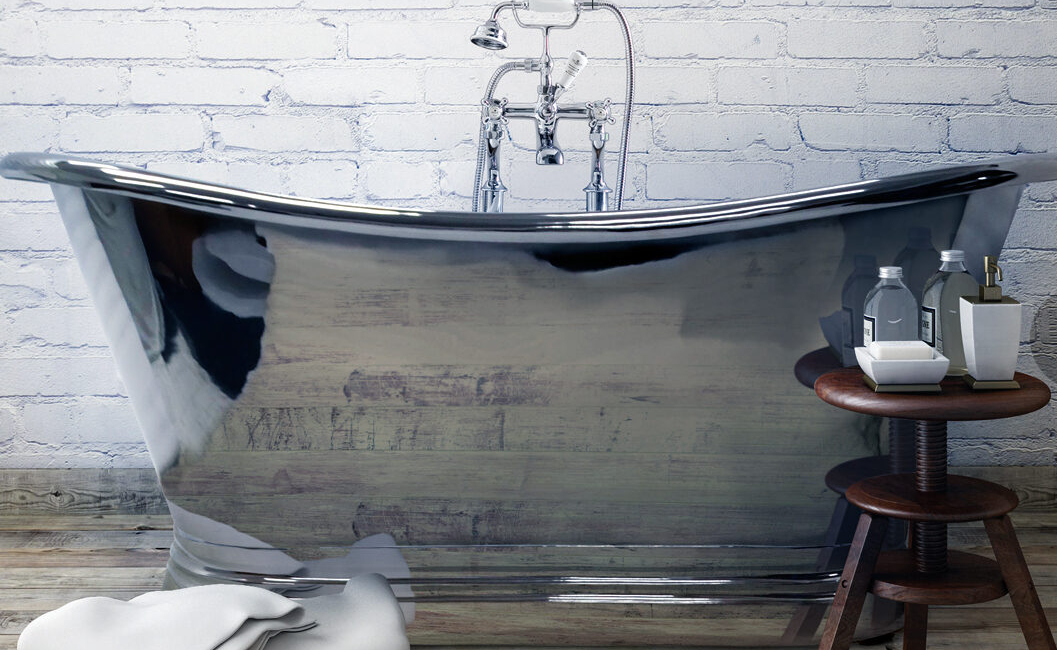 A sleek, curved bathtub is positioned against a white brick wall with a wooden stool nearby.