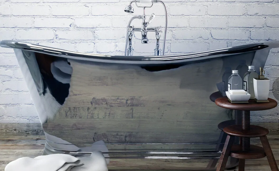 A sleek, curved bathtub is positioned against a white brick wall with a wooden stool nearby.