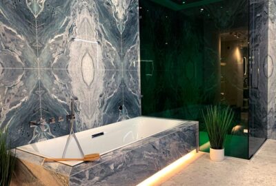 Stylish bathroom featuring marble walls, a modern bathtub, and contemporary lighting.