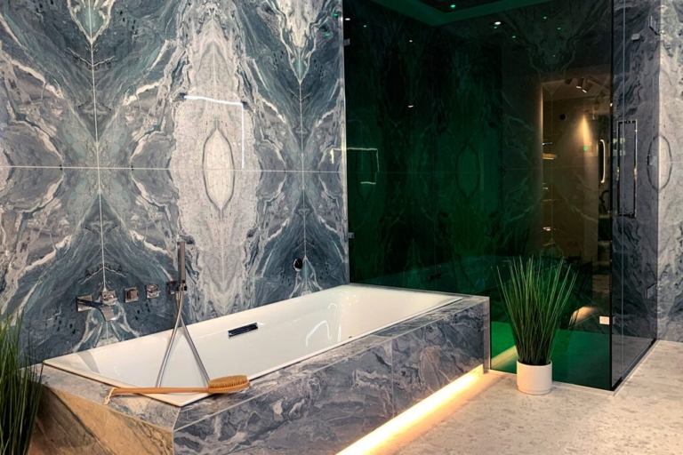Stylish bathroom featuring marble walls, a modern bathtub, and contemporary lighting.