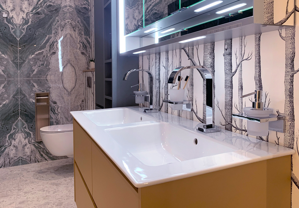 Modern bathroom featuring a double sink, stylish taps, and artistic tree-patterned wallpaper.