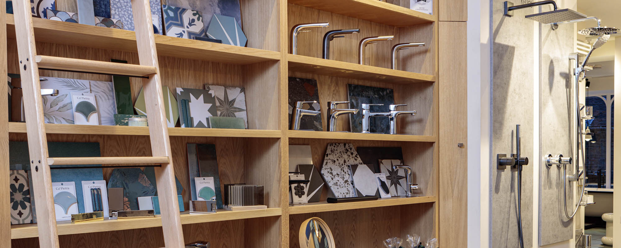 Wooden shelves with tiles, taps, and a ladder beside shower displays.