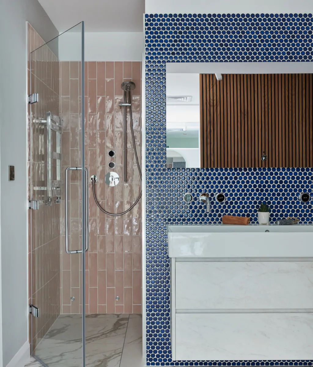 Contemporary bathroom featuring a shower, marble sink, and patterned blue and pink tiles.