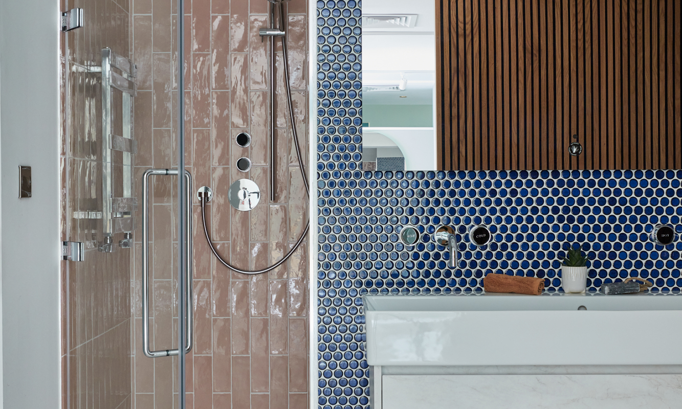 Contemporary bathroom featuring a shower, marble sink, and patterned blue and pink tiles.