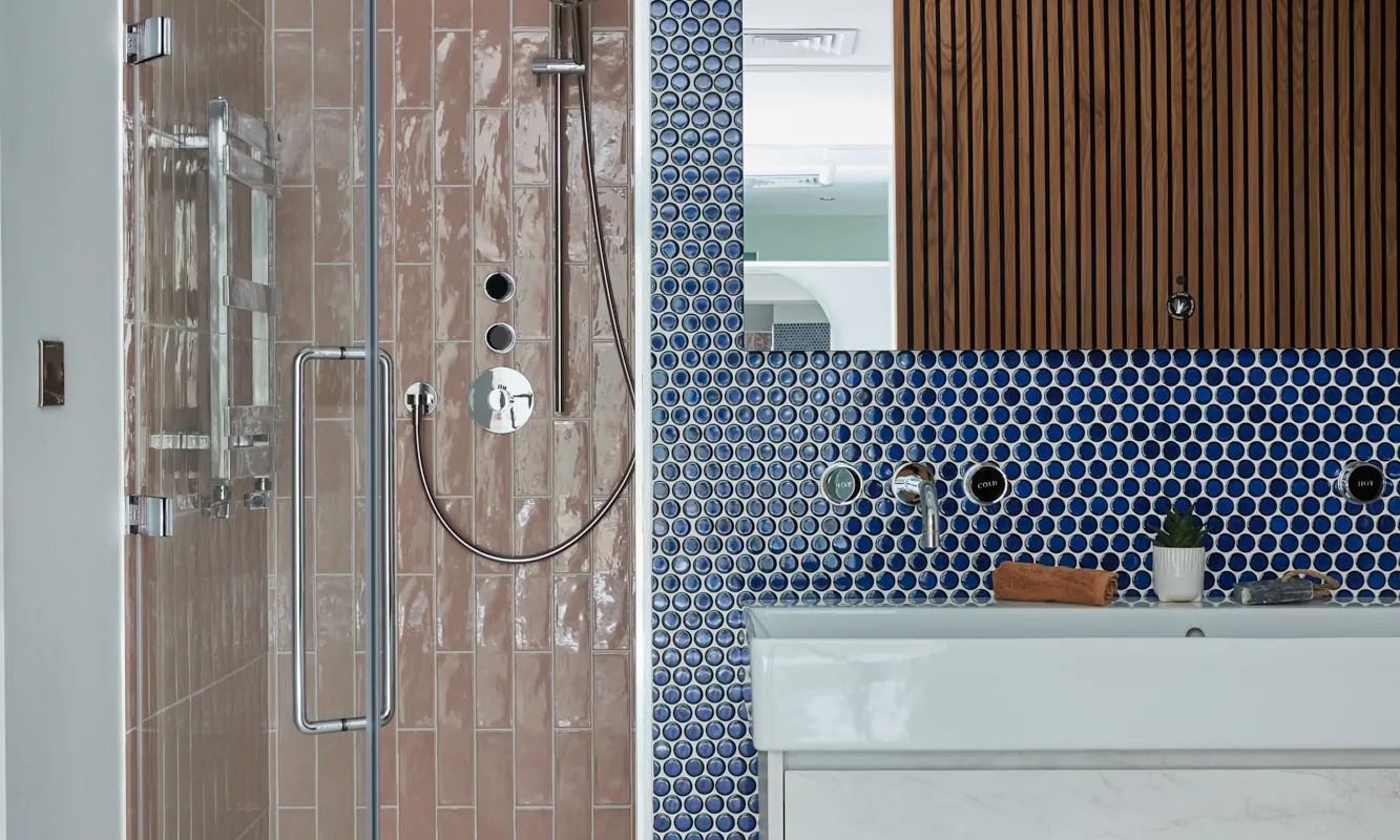 Contemporary bathroom featuring a shower, marble sink, and patterned blue and pink tiles.