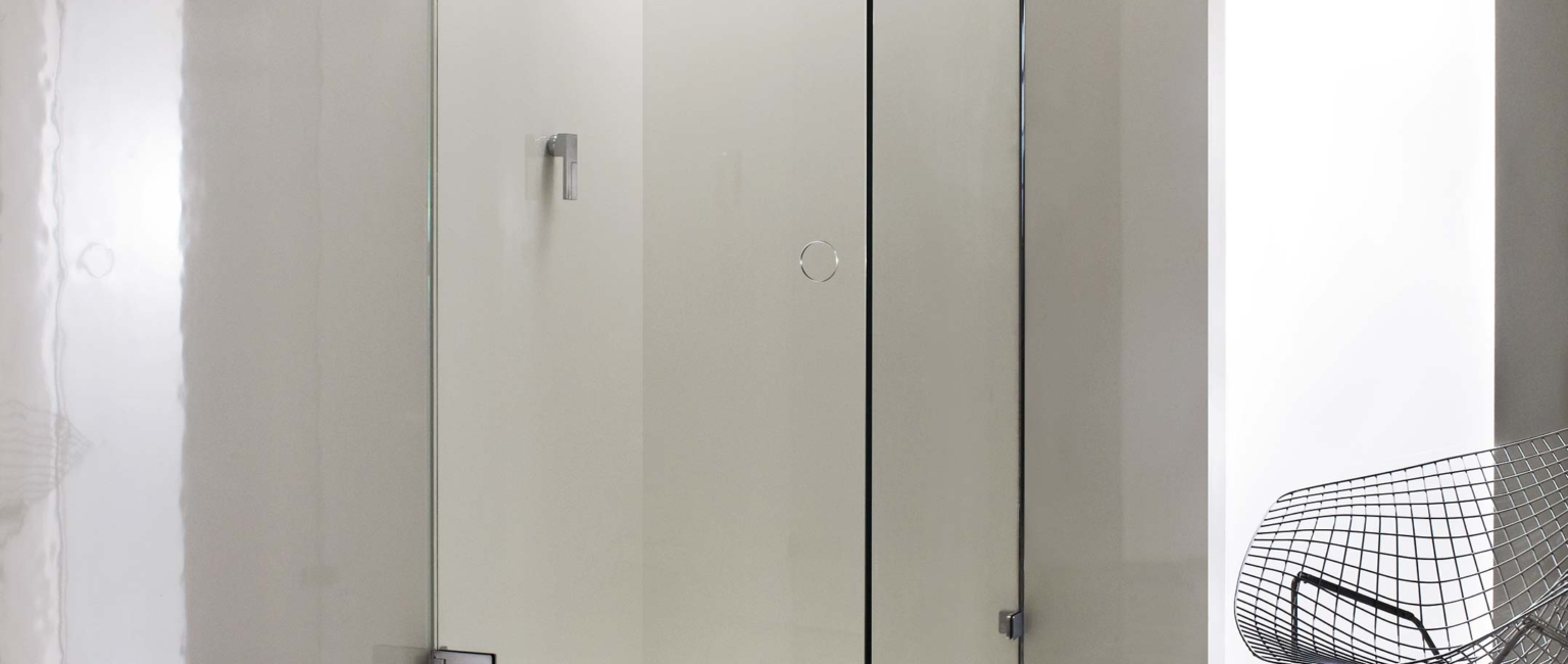 A modern glass shower enclosure is set on a patterned floor.