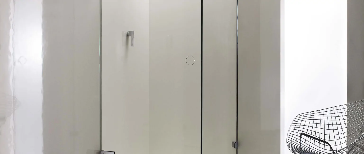 A modern glass shower enclosure is set on a patterned floor.