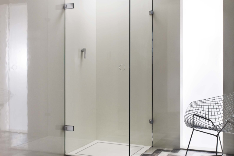 A modern glass shower enclosure is set on a patterned floor.