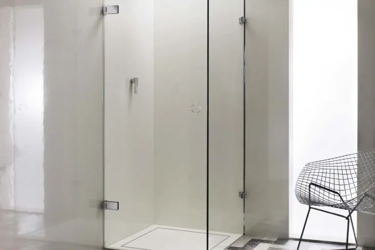 A modern glass shower enclosure is set on a patterned floor.