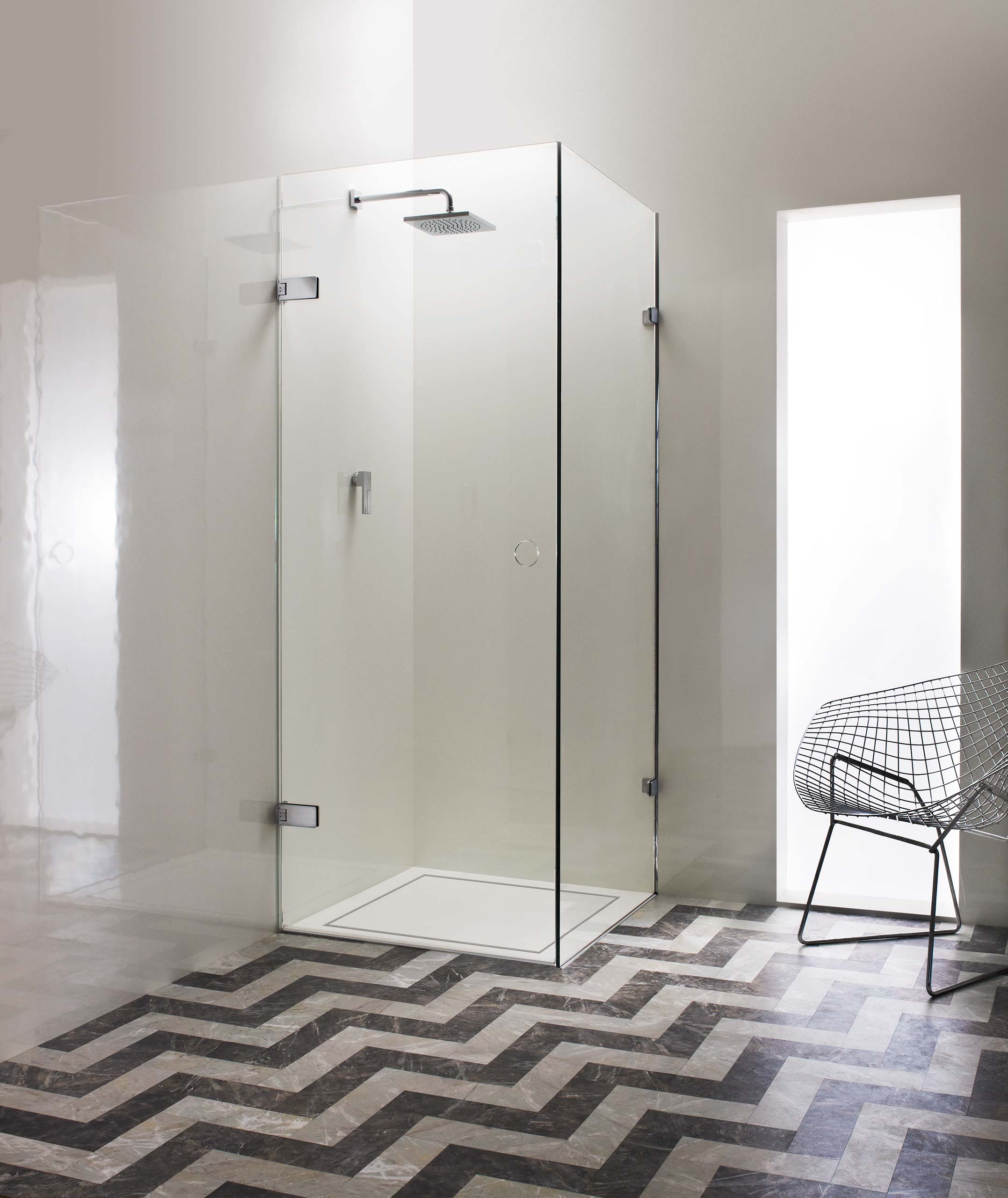 A modern glass shower enclosure is set on a patterned floor.