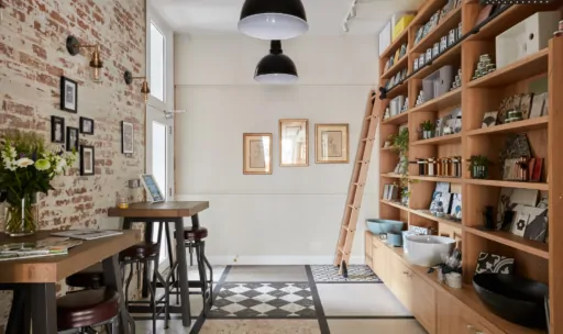 A stylish interior featuring wooden furniture, shelves filled with items, and decorative lighting.