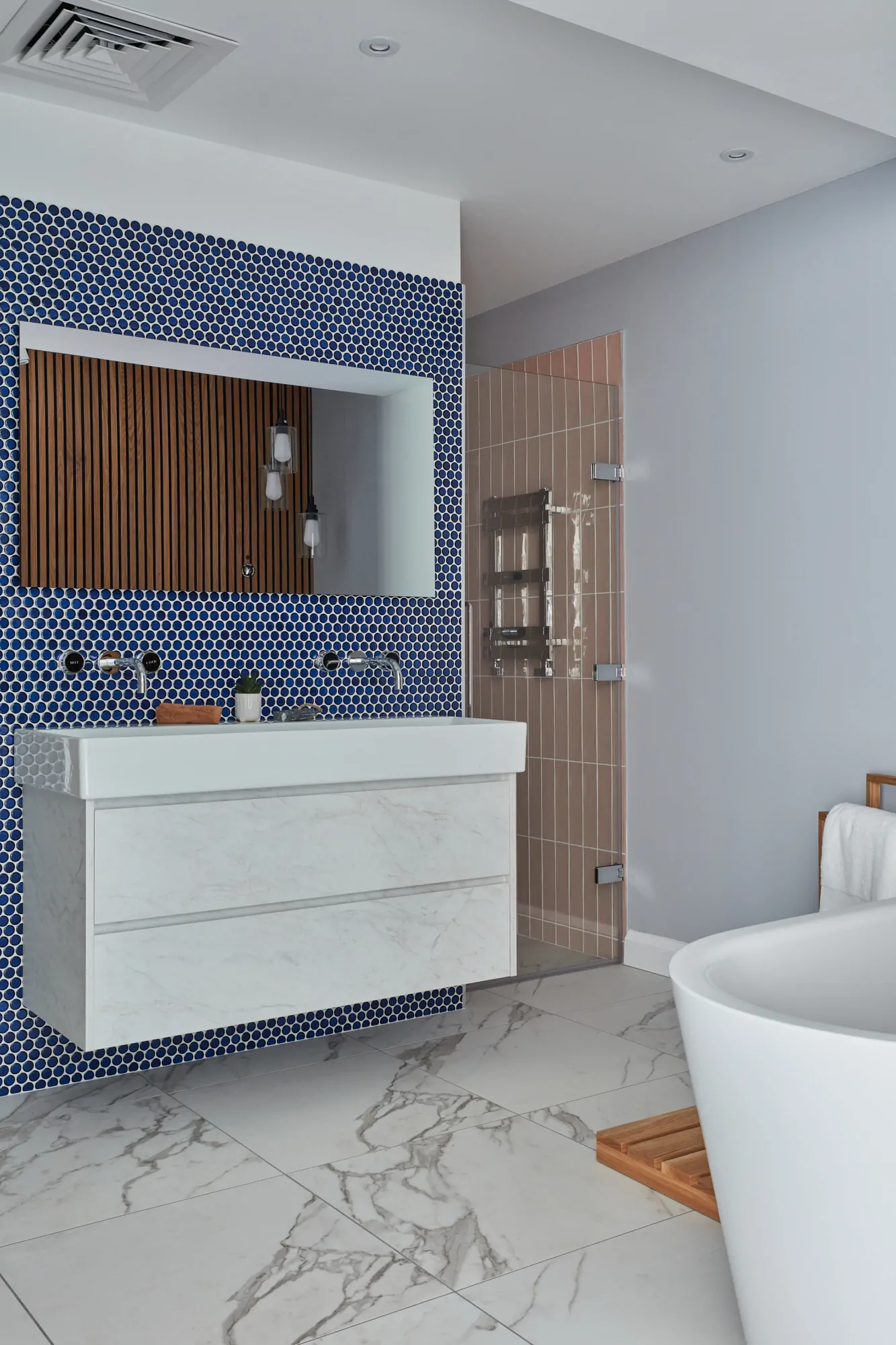 Modern bathroom with blue tile backsplash, floating vanity, and freestanding bathtub.