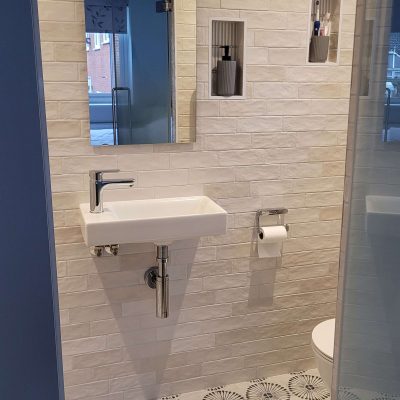 Compact bathroom with white subway tiles, floating sink, and modern patterned floor tiles