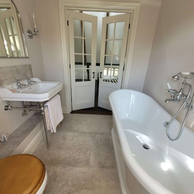 Luxurious bathroom with a freestanding white bathtub, chrome fixtures, and French double doors leading to another room