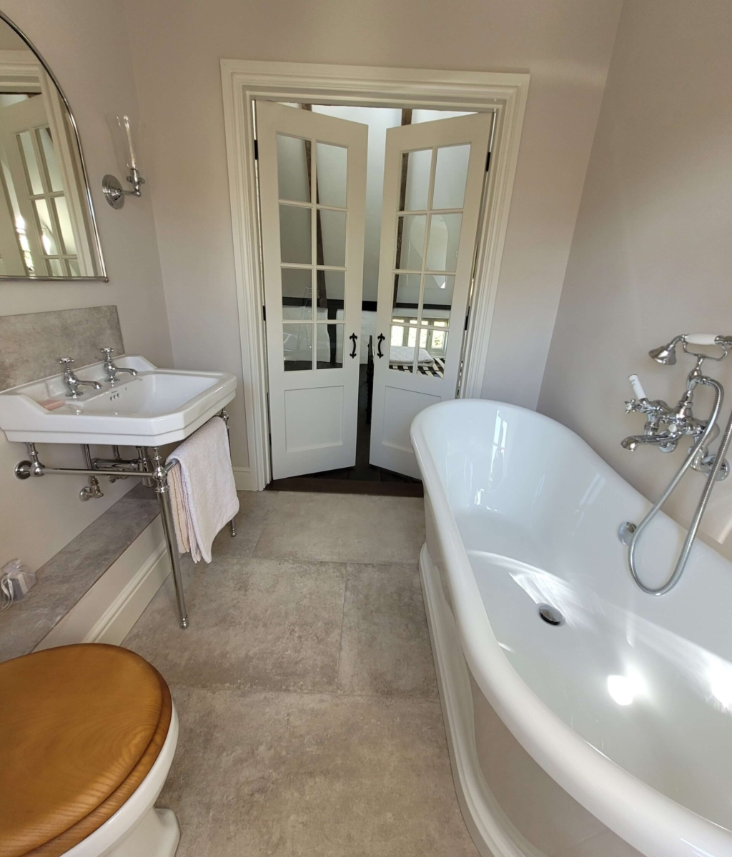 Luxurious bathroom with a freestanding white bathtub, chrome fixtures, and French double doors leading to another room