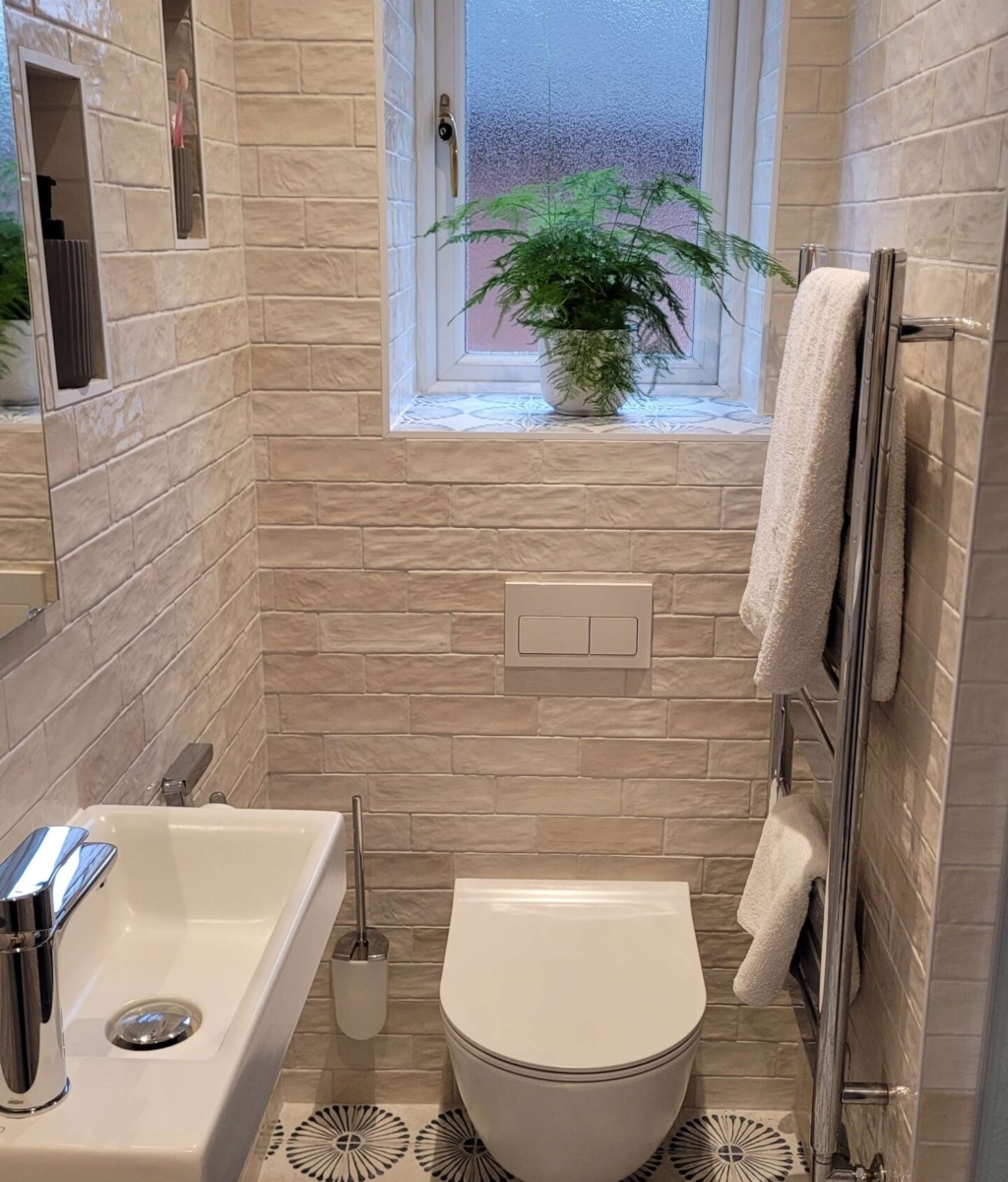 Narrow modern bathroom featuring a small floating sink, white subway tiles, and a large window with a potted plant