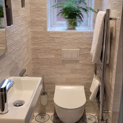 Narrow modern bathroom featuring a small floating sink, white subway tiles, and a large window with a potted plant