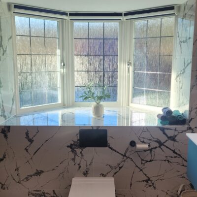 luxurious bathroom featuring a bay window, marble-clad walls