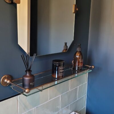 stylish bathroom with deep blue walls, a vintage-style sink, and bronze fixtures