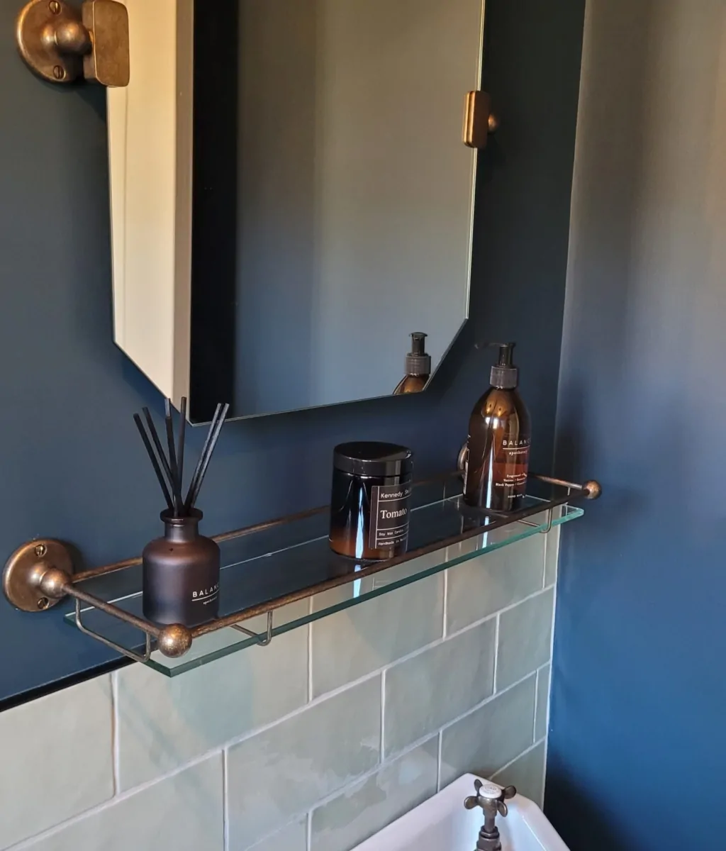 stylish bathroom with deep blue walls, a vintage-style sink, and bronze fixtures