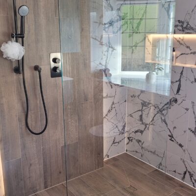 spacious walk-in shower with wood-effect tiles, marble feature walls, and a black rainfall showerhead