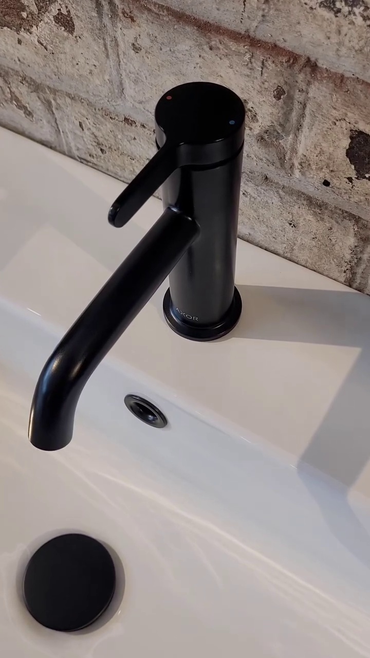Close-up of white ceramic basin with sleek chrome tap set against an industrial-style vanity with metal detailing.