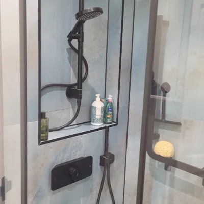 Black showerhead against a blue textured wall panel