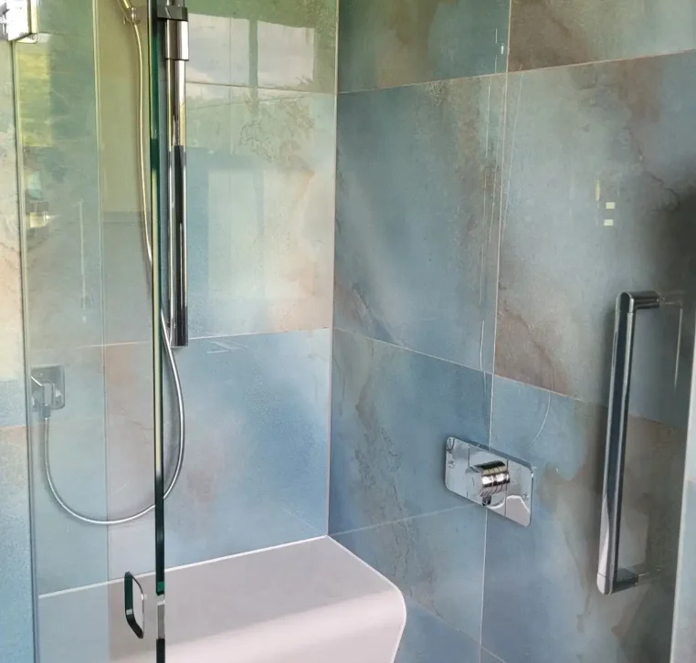 Walk-in shower with rainfall head and integrated bench.
