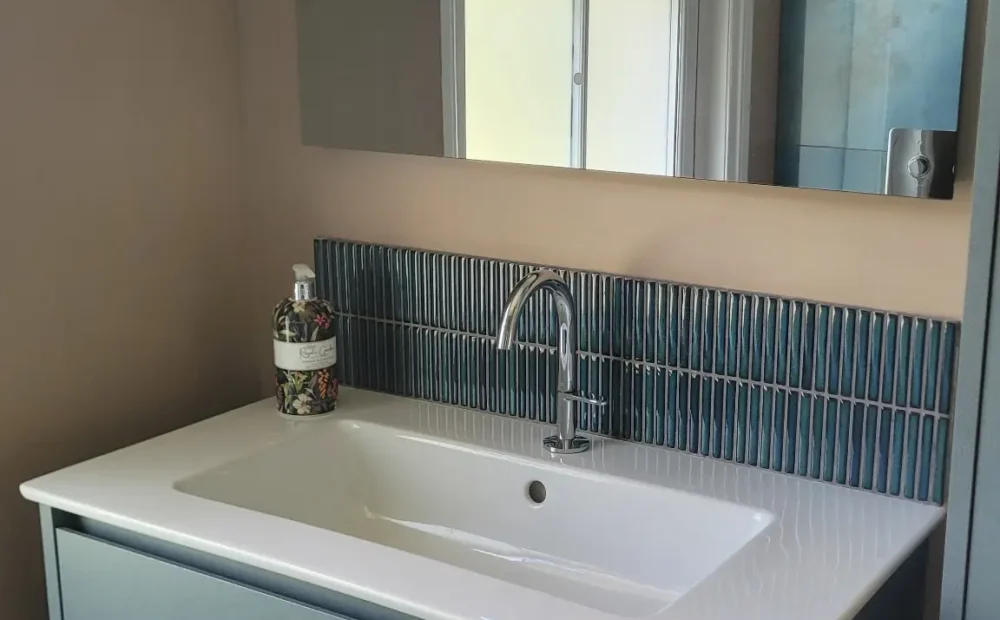Floating blue vanity unit under sash window with mirror