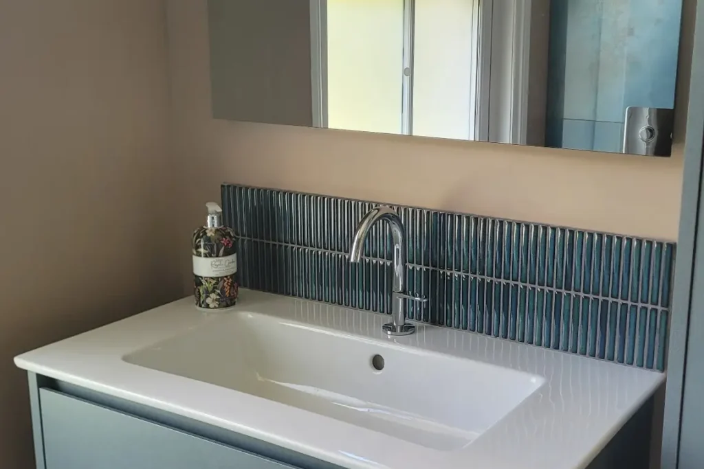 Floating blue vanity unit under sash window with mirror