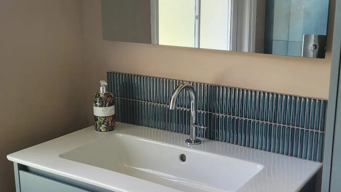 Floating blue vanity unit under sash window with mirror