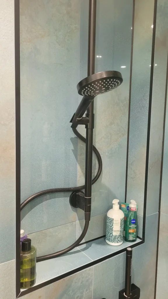 Close-up of modern black shower fitting on blue wall.