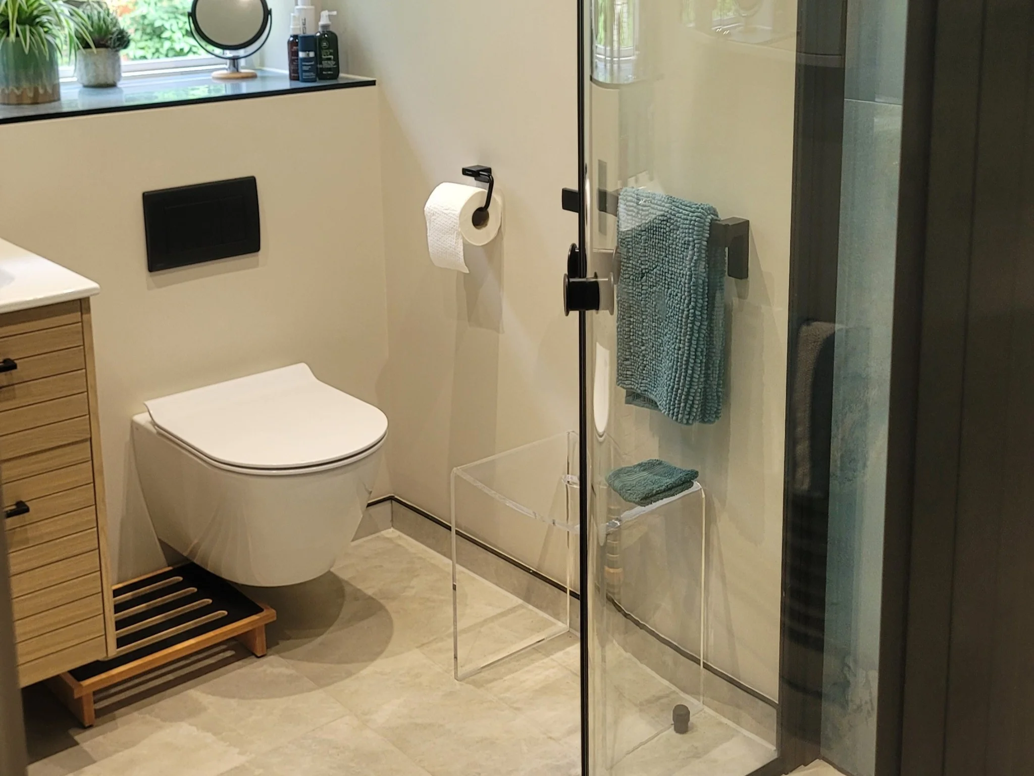 Floating toilet, vanity unit and glass shower in modern bathroom