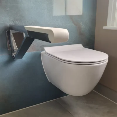 Floating toilet with modern white grab bar on blue wall.