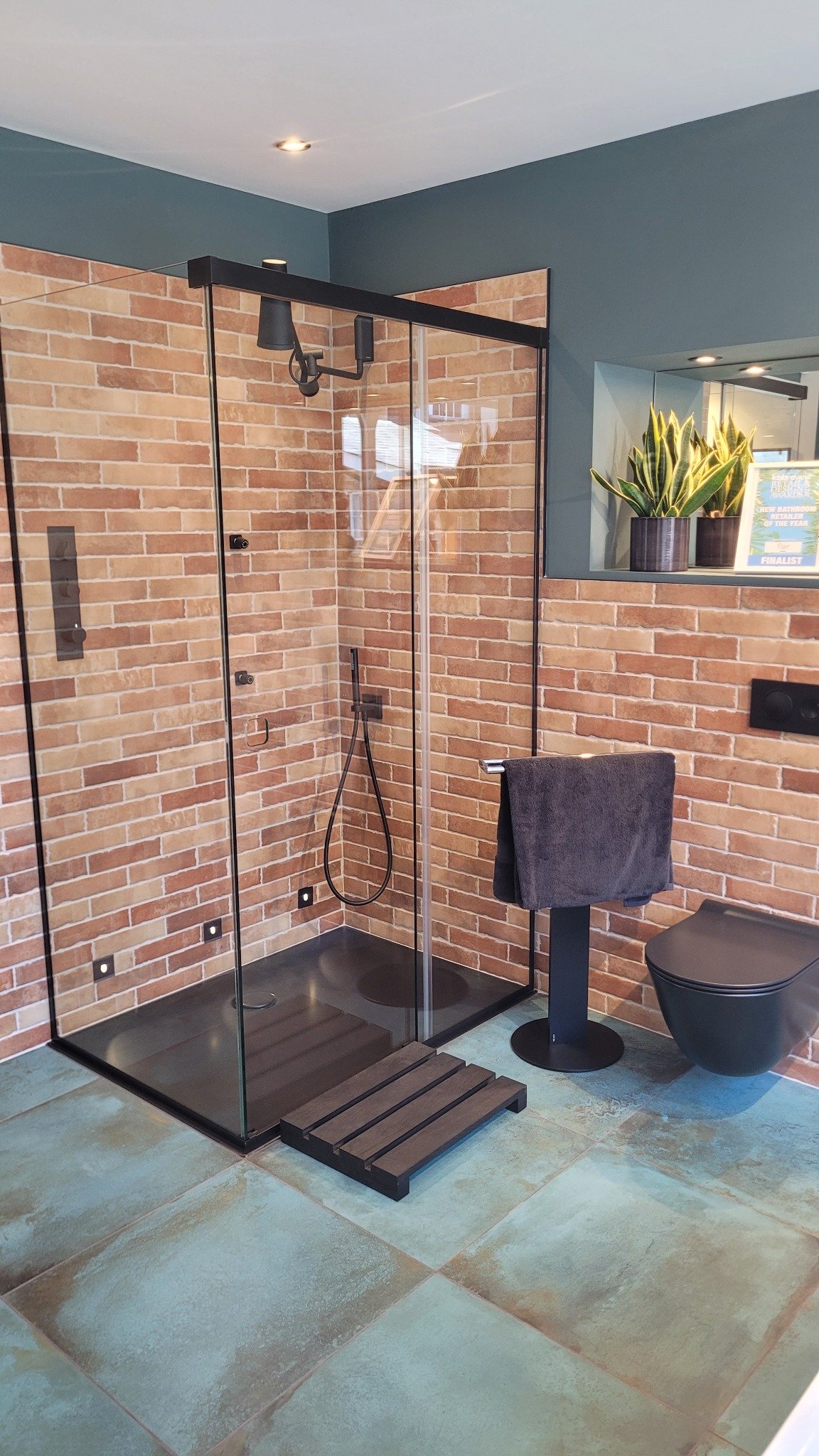 Contemporary shower area with glass partition, modern brick walls, and stylish black fixtures.