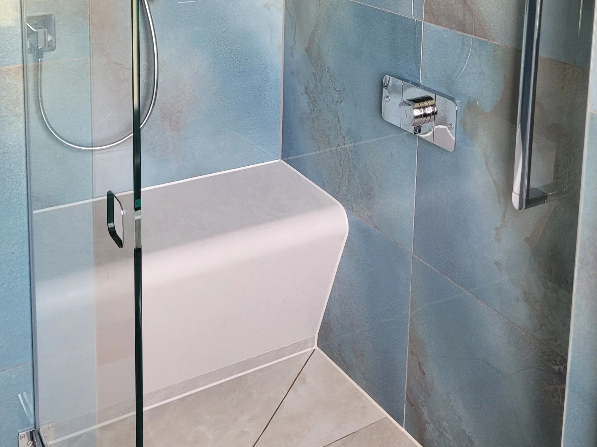 Built-in shower bench with blue tiles and chrome fixtures