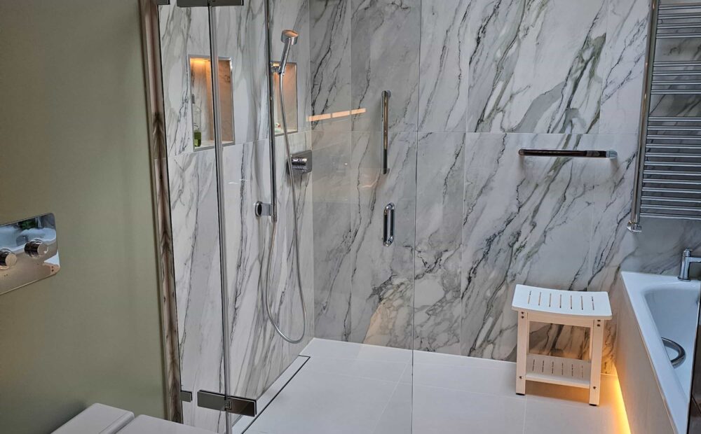 A contemporary wetroom featuring a tiled design with a bath opposite the shower and elegant LED lighting.