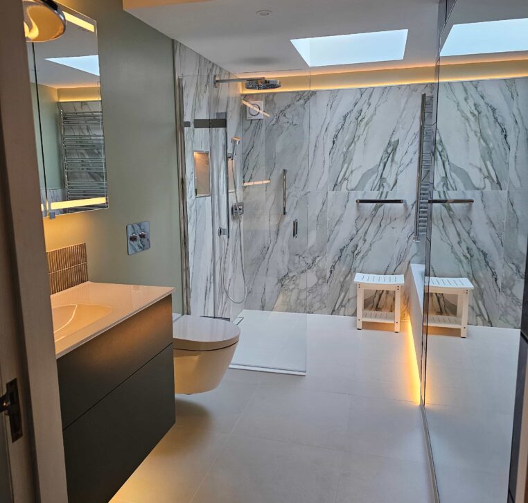 Full view of the tiled wetroom with luxurious LED lighting illuminating the bath, shower, and niches.
