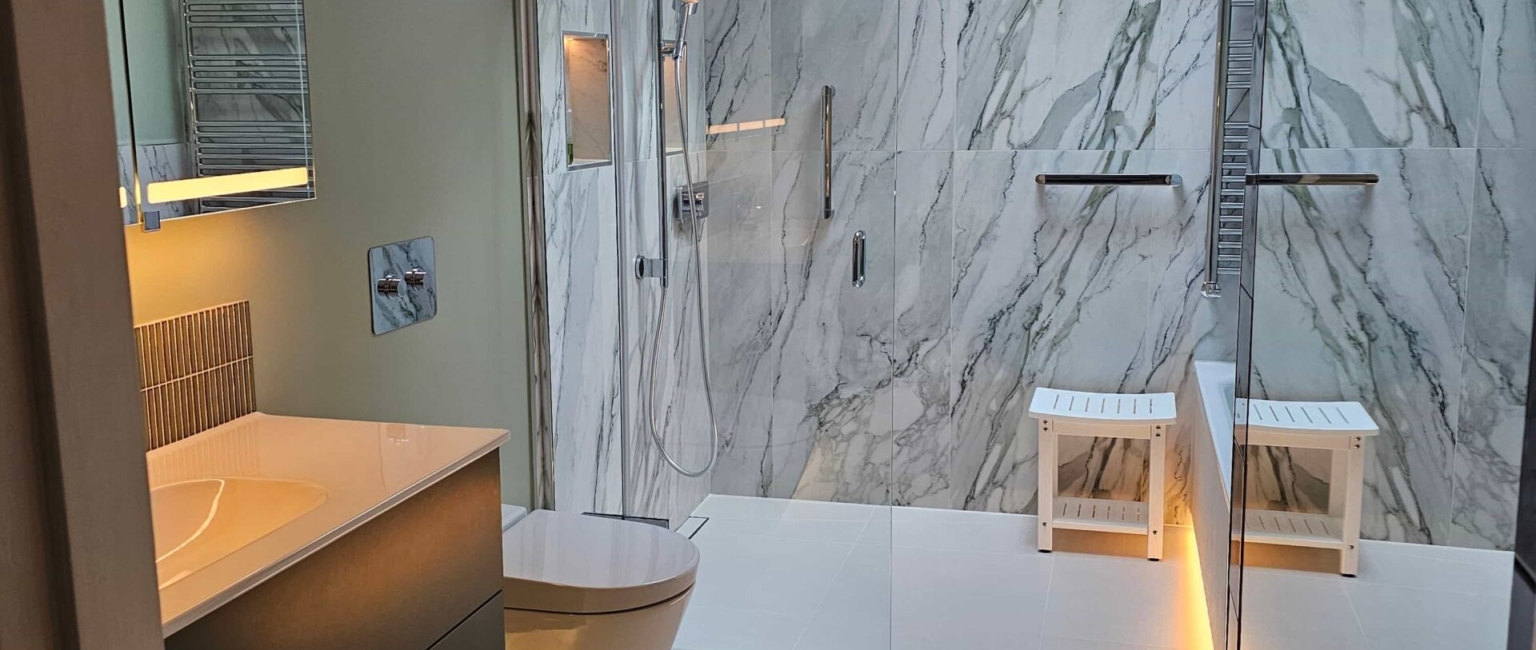 Full view of the tiled wetroom with luxurious LED lighting illuminating the bath, shower, and niches.