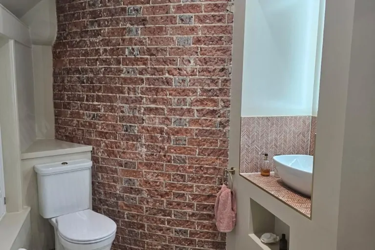 Light-filled wet room with exposed oast brickwork, wall-hung toilet and walk-in shower