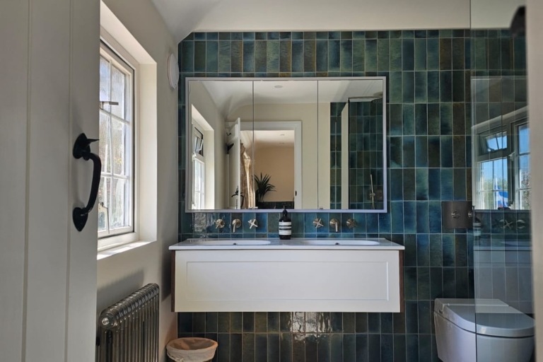Spacious en-suite wet room with blue tiled walls, floating vanity and wall-hung toilet