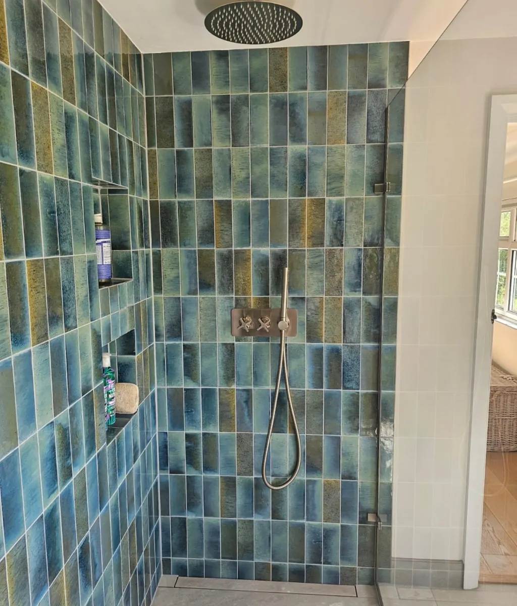 Walk-in shower with blue glazed wall tiles and overhead rainfall shower