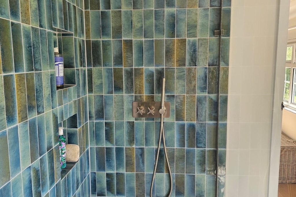 Walk-in shower with blue glazed wall tiles and overhead rainfall shower