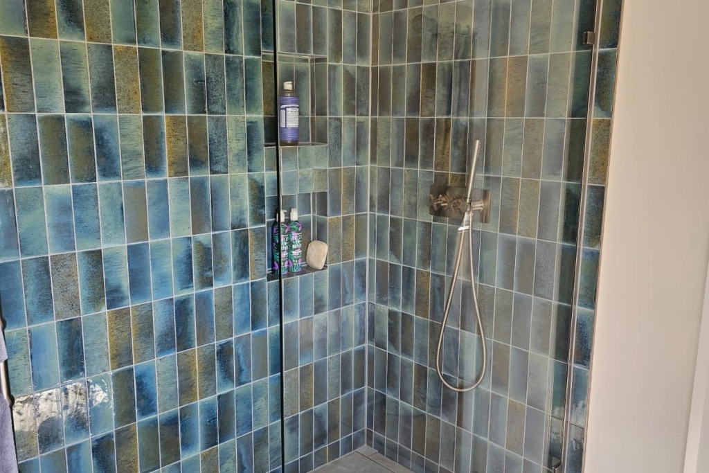 Spacious walk-in wet room shower with blue tiles and glass screen