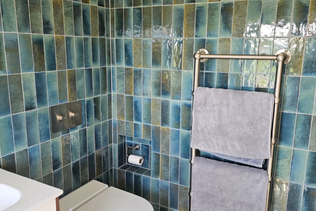 Wall-hung toilet with blue tiled walls and heated towel rail