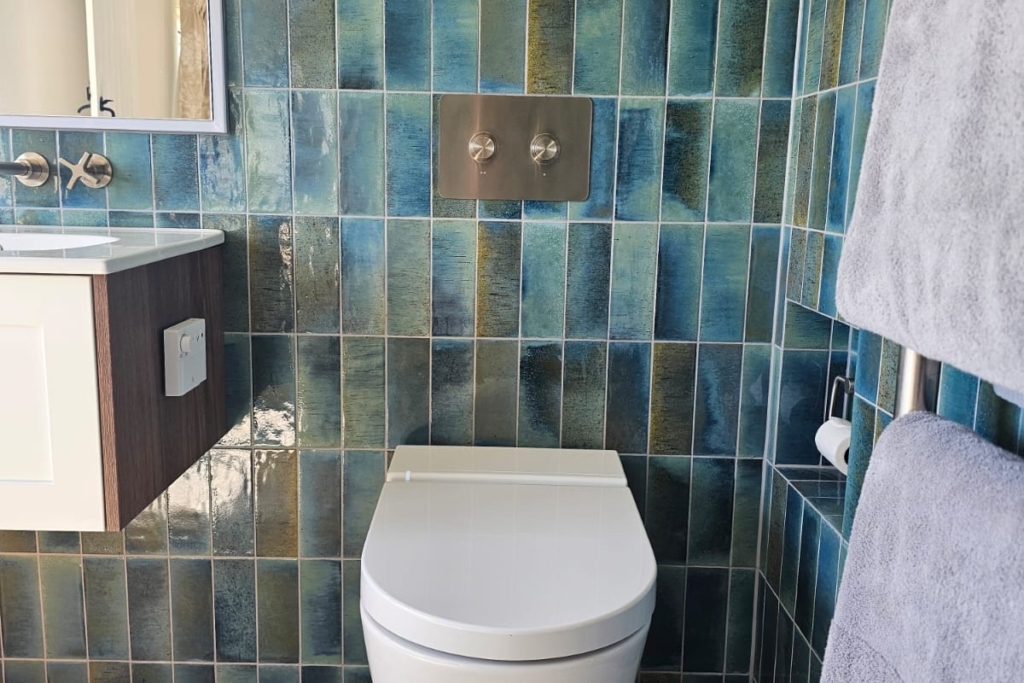 Wall-hung toilet set against blue glazed tiles in a modern en-suite wet room