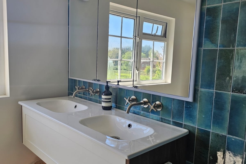 Floating white vanity with basin, window and blue tiled wall