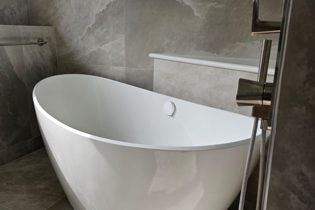 Freestanding white bath with wall-mounted taps and heated towel rail