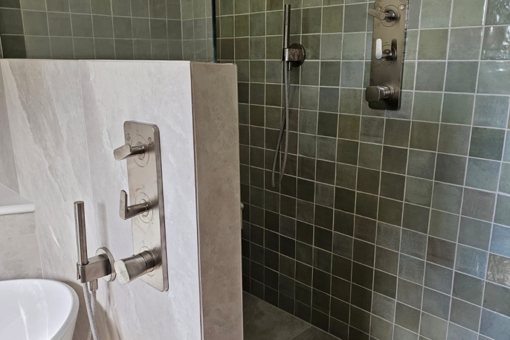 Walk-in shower with green textured tiles and wall-mounted shower controls