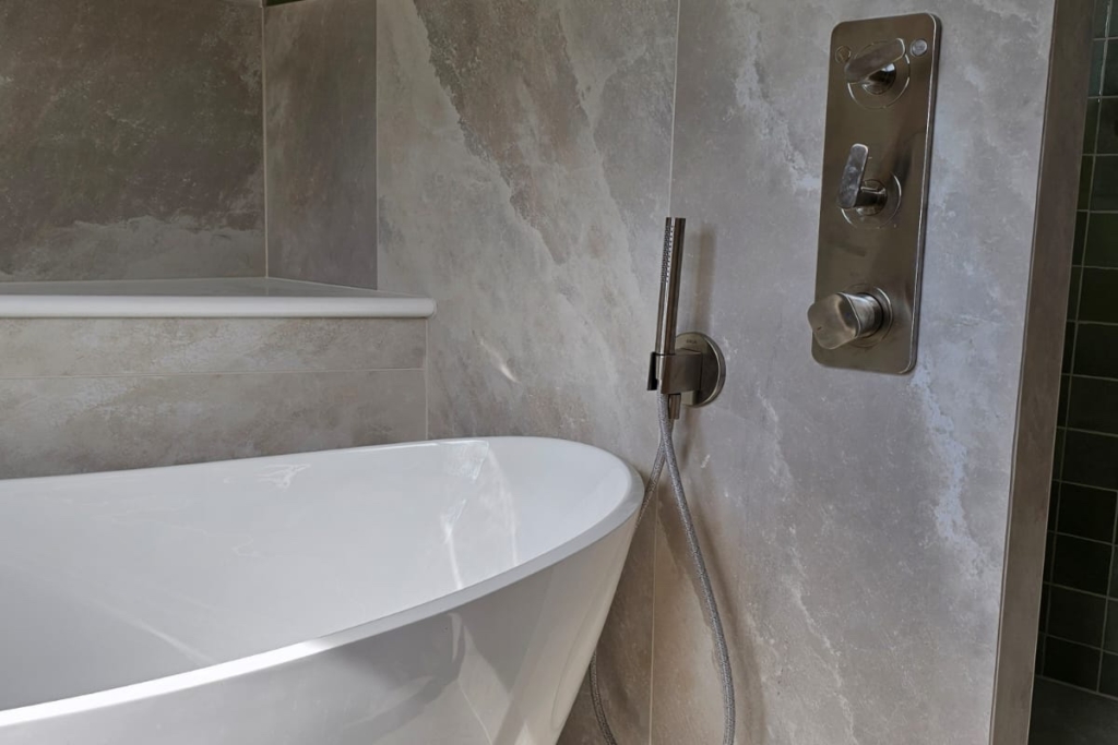 Freestanding bath beside a walk-in shower with stone-effect wall tiles